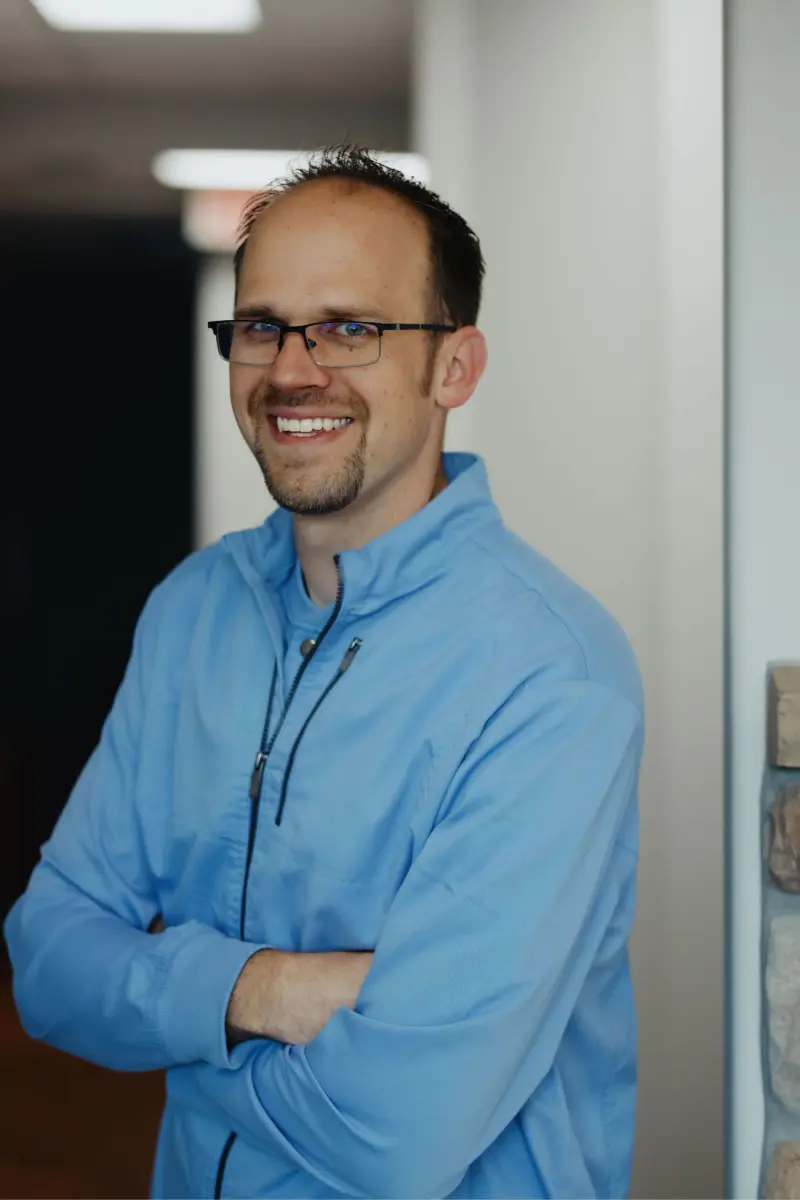 Dr. Adam Milmont in a blue shirt, smiling, at Hilltop Family Dental